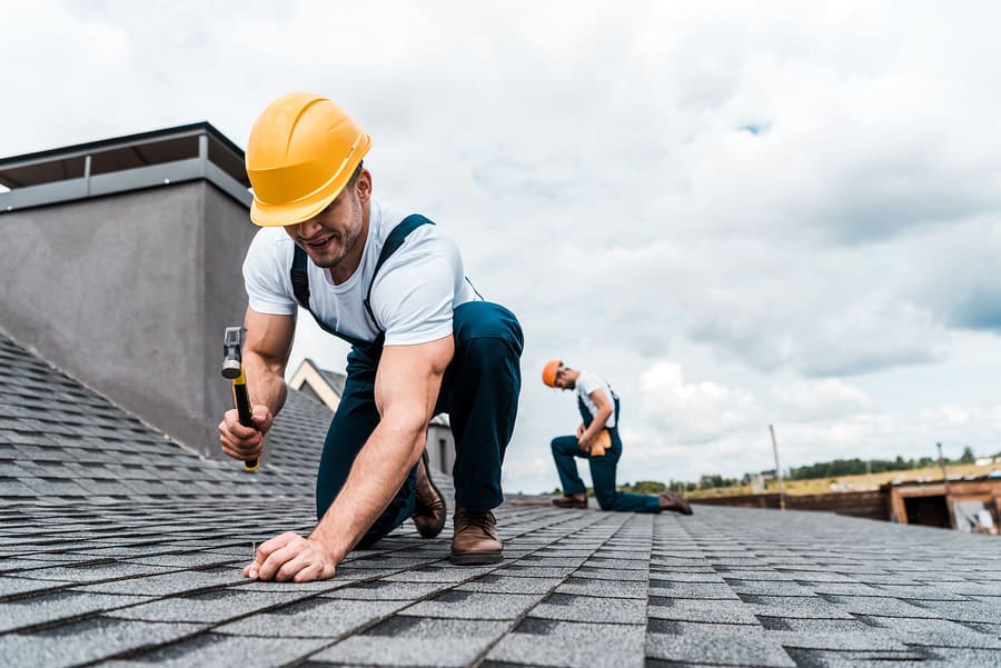 Roofer working on asphalt shingles during a repair